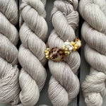 Bundles of light gray yarn arranged neatly with a decorative clip on top.