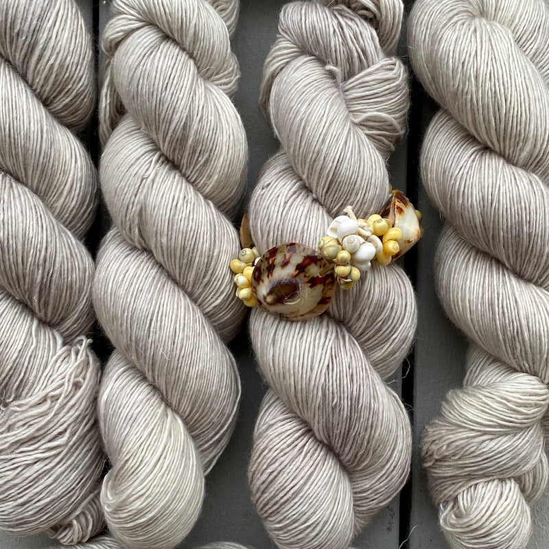 Bundles of light gray yarn arranged neatly with a decorative clip on top.